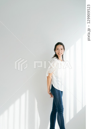 窓辺に立つデニムの女性（縦長） 129909523