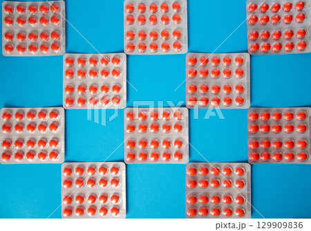 Blister packs with red pills in a checkerboard pattern on a blue background. Concept of pills for depression and anxiety, antidepressants, treatment Blister packs with red pills in a checkerboard pattern on a blue background. Concept of pills for depression and anxiety, antidepressants, treatment 129909836