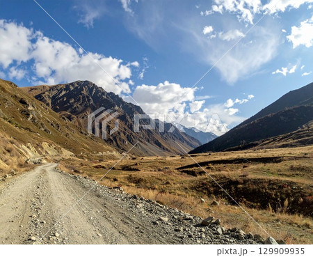 砂利道が続く山岳の谷・青空と雲の風景 砂利道が続く山岳の谷・青空と雲の風景 129909935
