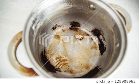 Burnt food in a saucepan, close-up. Black burnt food deposits on non-stick coating, harm Burnt food in a saucepan, close-up. Black burnt food deposits on non-stick coating, harm 129909963