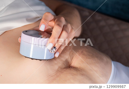 Girl gives herself an anti-cellulite massage on her stomach with a portable vacuum massager, close-up Girl gives herself an anti-cellulite massage on her stomach with a portable vacuum massager, close-up 129909987