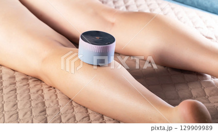 Girl gives herself a massage with a portable vacuum massager on her body. Anti-cellulite and relaxing massage, close-up 129909989