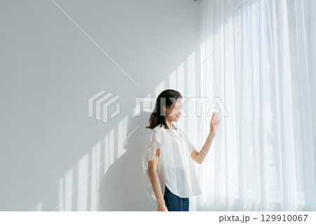 窓辺に立つデニムの女性 129910067
