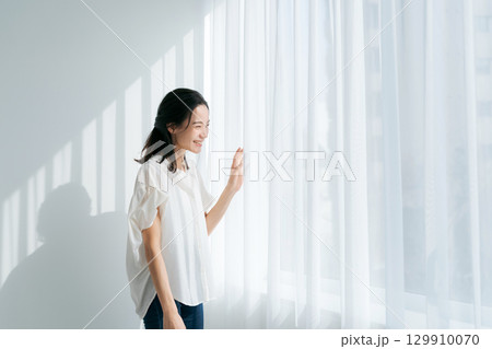 窓辺に立つデニムの女性 窓辺に立つデニムの女性 129910070
