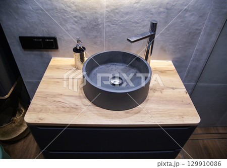 Stone grey wash basin in wall hung cabinet in bathroom with chrome faucet. Modern stylish design. Stone grey wash basin in wall hung cabinet in bathroom with chrome faucet. Modern stylish design. 129910086