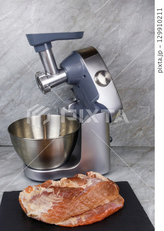 Electric eat grinder and fresh meat on kitchen table. Preparation of minced meat 129910211