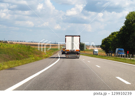 A truck with a semi-trailer delivers cargo along the highway to the marketplace. Delivery service from an online store to the buyer. Copy space for text A truck with a semi-trailer delivers cargo along the highway to the marketplace. Delivery service from an online store to the buyer. Copy space for text 129910239