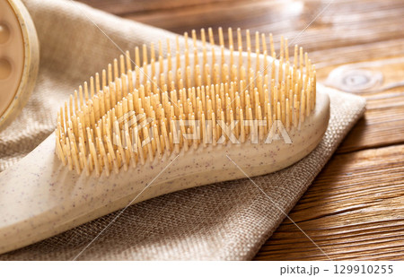 Brown massage comb on wooden background, close-up 129910255