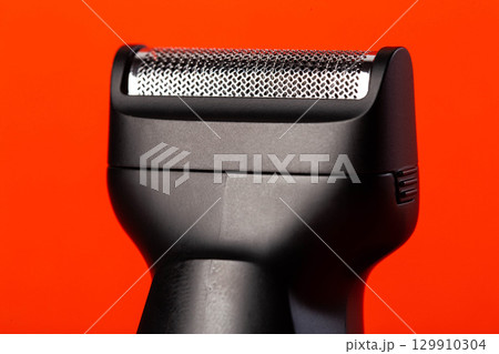 Modern shaving head on a red background. Beard care, close-up Modern shaving head on a red background. Beard care, close-up 129910304