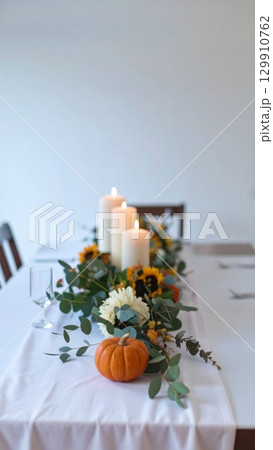 Festive Table Centerpiece with Candles Pumpkins and Sunflowers in White Room 129910762