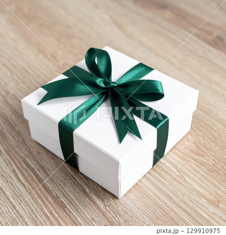 Elegant White Gift Box Tied with Green Ribbon on Light Wooden Background 129910975