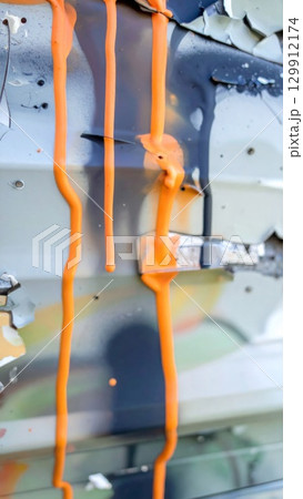 Bright Orange Paint Dripping Down a Textured Grey Wall Abstract Background Bright Orange Paint Dripping Down a Textured Grey Wall Abstract Background 129912174