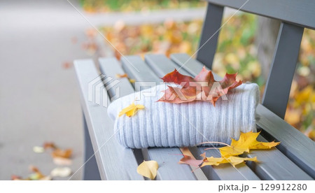Cozy White Sweater and Autumn Leaves on a Gray Bench in Natural Light 129912280