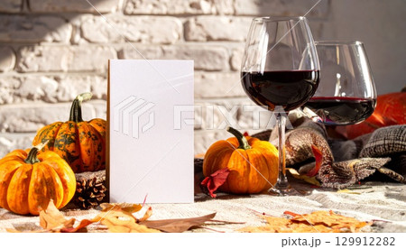 Autumnal Still Life with Red Wine Pumpkins and Blank Card Against a White Brick Wall 129912282