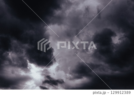 A stormy sky filled with ominous, dark heavy low clouds, creating a dramatic scene. Moody shot of a gloomy grey sky filled with swirling, storm clouds. Stormy weather. Before storm, rainstorm. 129912389