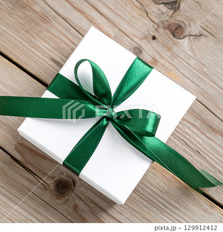 White Gift Box with Green Ribbon on Rustic Wooden Surface for Celebration White Gift Box with Green Ribbon on Rustic Wooden Surface for Celebration 129912412