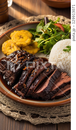 Delicious colombian posta negra cartagenera with rice and tostones on a rustic plate 129913071