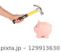 Man holding a hammer and breaking a piggy bank 129913630