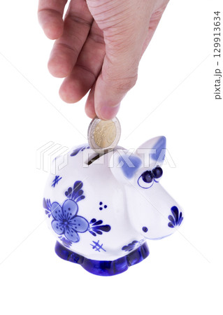 Piggy bank in a shape of a cow with blue ornament, coin falling 129913634