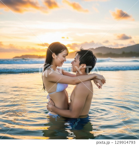 夕日の海に入り寄り添う日本人男女カップル 129914793