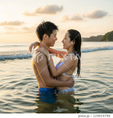 夕日の海に入り寄り添う日本人男女カップル 129914799