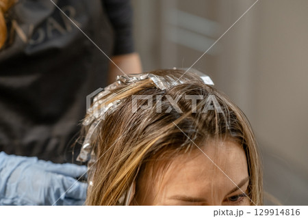 Hair coloring process in a modern salon with a stylist applying foils during afternoon session 129914816