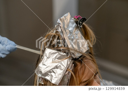 Hair coloring process in a salon with foils highlighting strands during a busy afternoon appointment 129914839