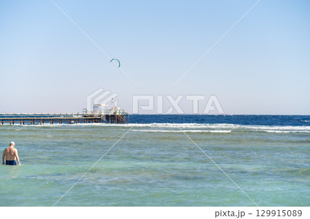 Kite surfing activity at a beach pier in Egypt on a sunny day with clear skies 129915089
