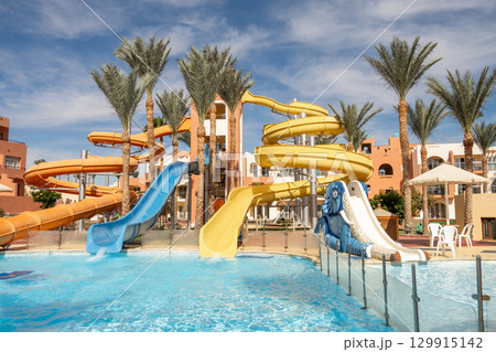 Water slides and tropical palm trees at a resort in Egypt during sunny weather 129915142