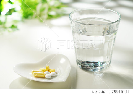 錠剤とカプセルの薬とグラスに入ったミネラルウォーター 129916111