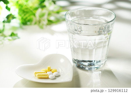錠剤とカプセルの薬とグラスに入ったミネラルウォーター 129916112