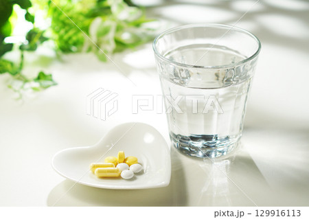 錠剤とカプセルの薬とグラスに入ったミネラルウォーター 129916113