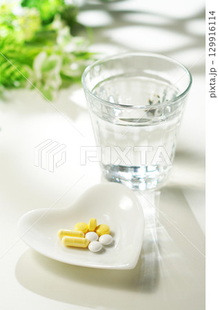 錠剤とカプセルの薬とグラスに入ったミネラルウォーター 129916114