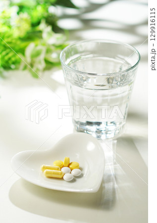 錠剤とカプセルの薬とグラスに入ったミネラルウォーター 錠剤とカプセルの薬とグラスに入ったミネラルウォーター 129916115
