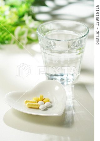 錠剤とカプセルの薬とグラスに入ったミネラルウォーター 129916116
