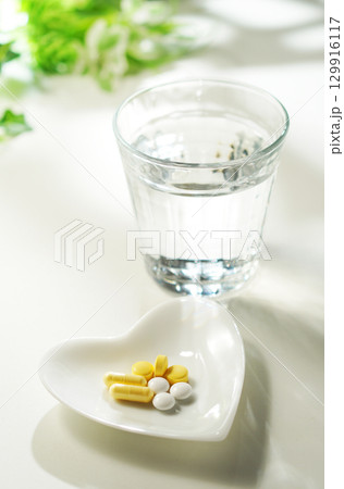 錠剤とカプセルの薬とグラスに入ったミネラルウォーター 錠剤とカプセルの薬とグラスに入ったミネラルウォーター 129916117