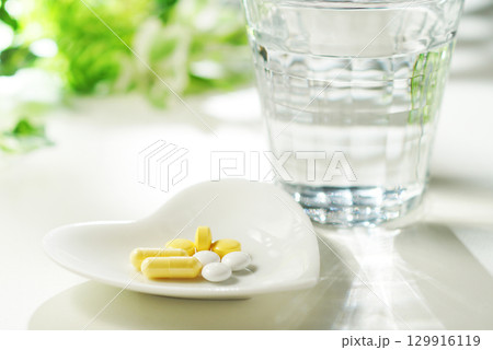 錠剤とカプセルの薬とグラスに入ったミネラルウォーター 129916119