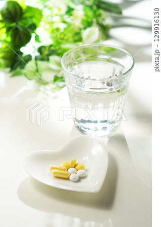 錠剤とカプセルの薬とグラスに入ったミネラルウォーター 129916130