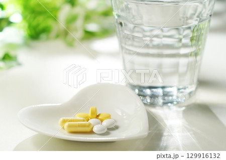 錠剤とカプセルの薬とグラスに入ったミネラルウォーター 129916132