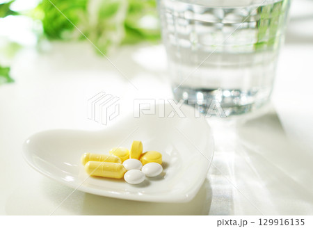 錠剤とカプセルの薬とグラスに入ったミネラルウォーター 129916135