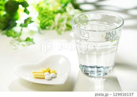 錠剤とカプセルの薬とグラスに入ったミネラルウォーター 129916137