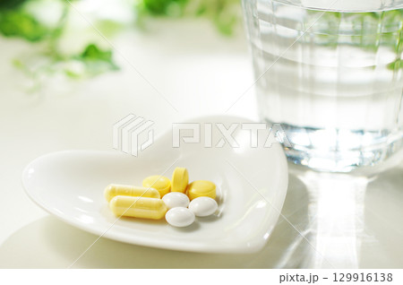 錠剤とカプセルの薬とグラスに入ったミネラルウォーター 129916138