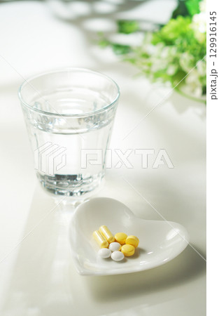 錠剤とカプセルの薬とグラスに入ったミネラルウォーター 129916145