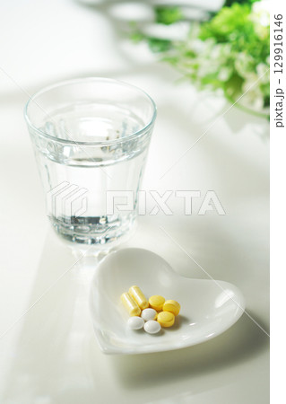 錠剤とカプセルの薬とグラスに入ったミネラルウォーター 129916146