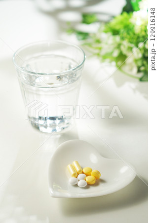 錠剤とカプセルの薬とグラスに入ったミネラルウォーター 129916148