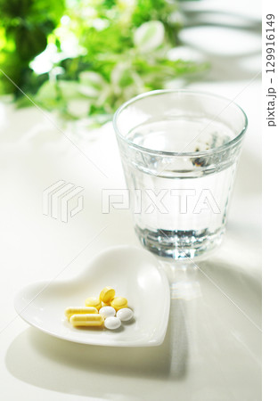錠剤とカプセルの薬とグラスに入ったミネラルウォーター 129916149