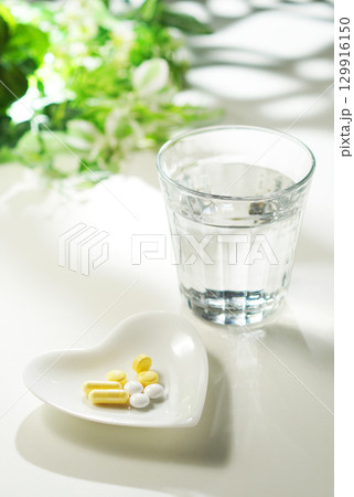 錠剤とカプセルの薬とグラスに入ったミネラルウォーター 129916150