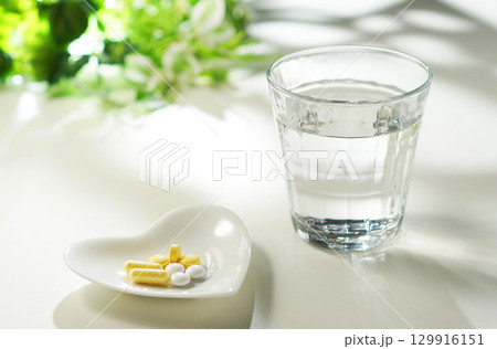 錠剤とカプセルの薬とグラスに入ったミネラルウォーター 129916151
