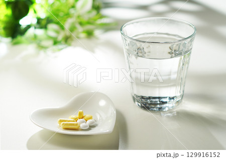 錠剤とカプセルの薬とグラスに入ったミネラルウォーター 129916152