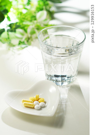 錠剤とカプセルの薬とグラスに入ったミネラルウォーター 錠剤とカプセルの薬とグラスに入ったミネラルウォーター 129916153